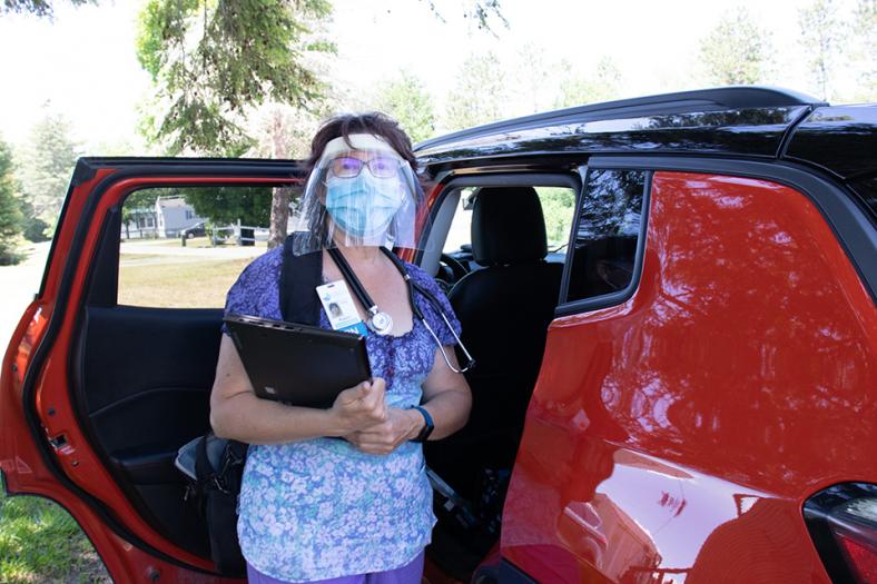 A VNH nurse standing beside her car